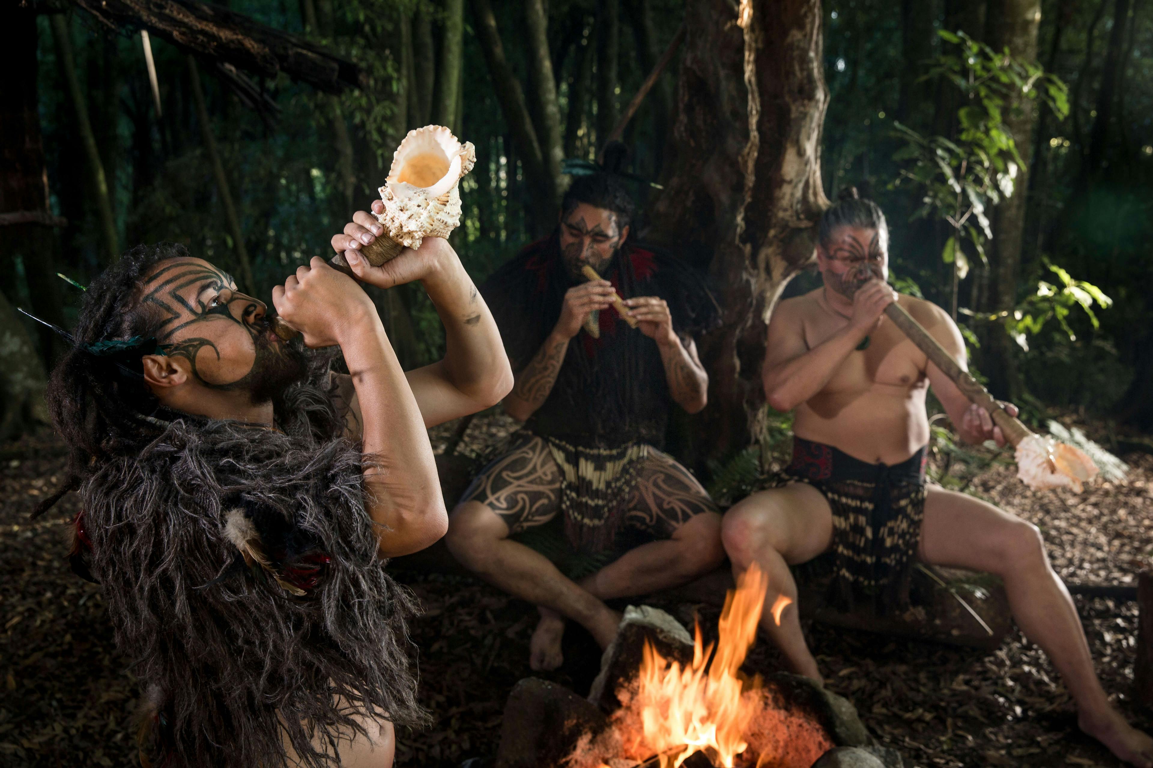 Photo of Maori people sitting by a fire.