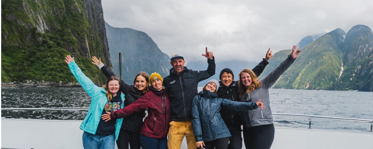 Group of people pose for a photo on a cruise in Milford Sound in New Zealand