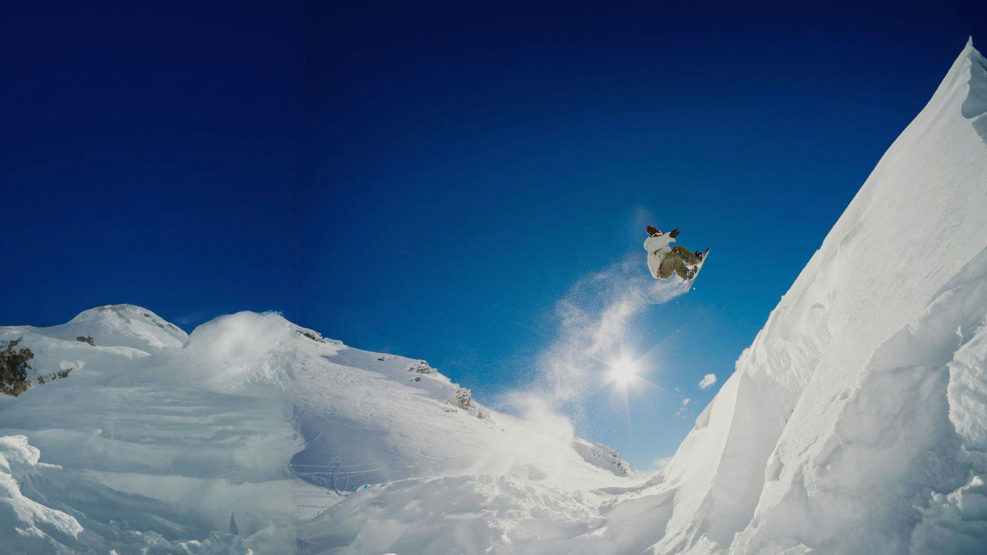 Snowboarder does a big jump on The Remarkables ski slopes in New Zealand