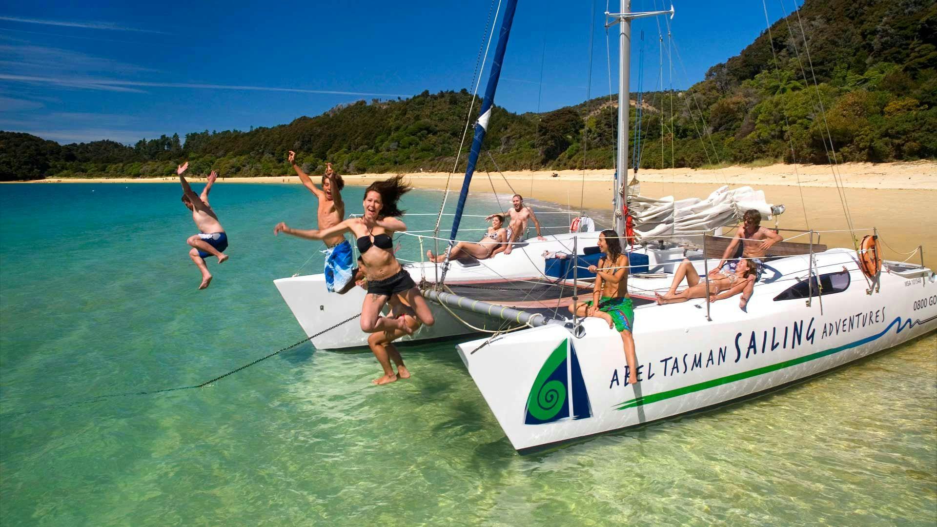 People jump off a catamaran into the water