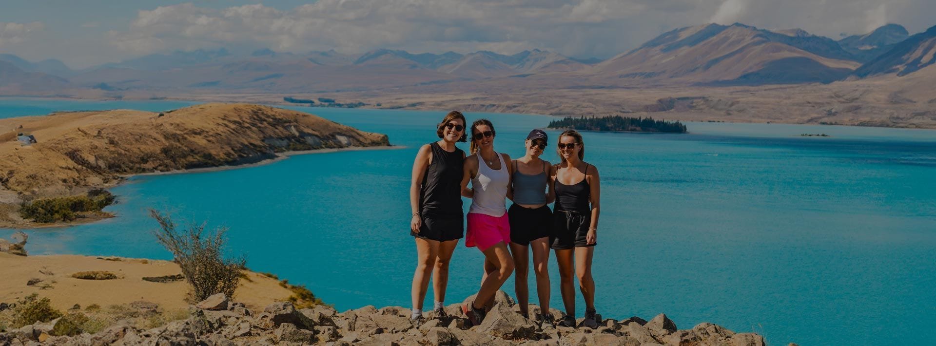 Group of young women pose for a photo overlooking Lake Tekapo