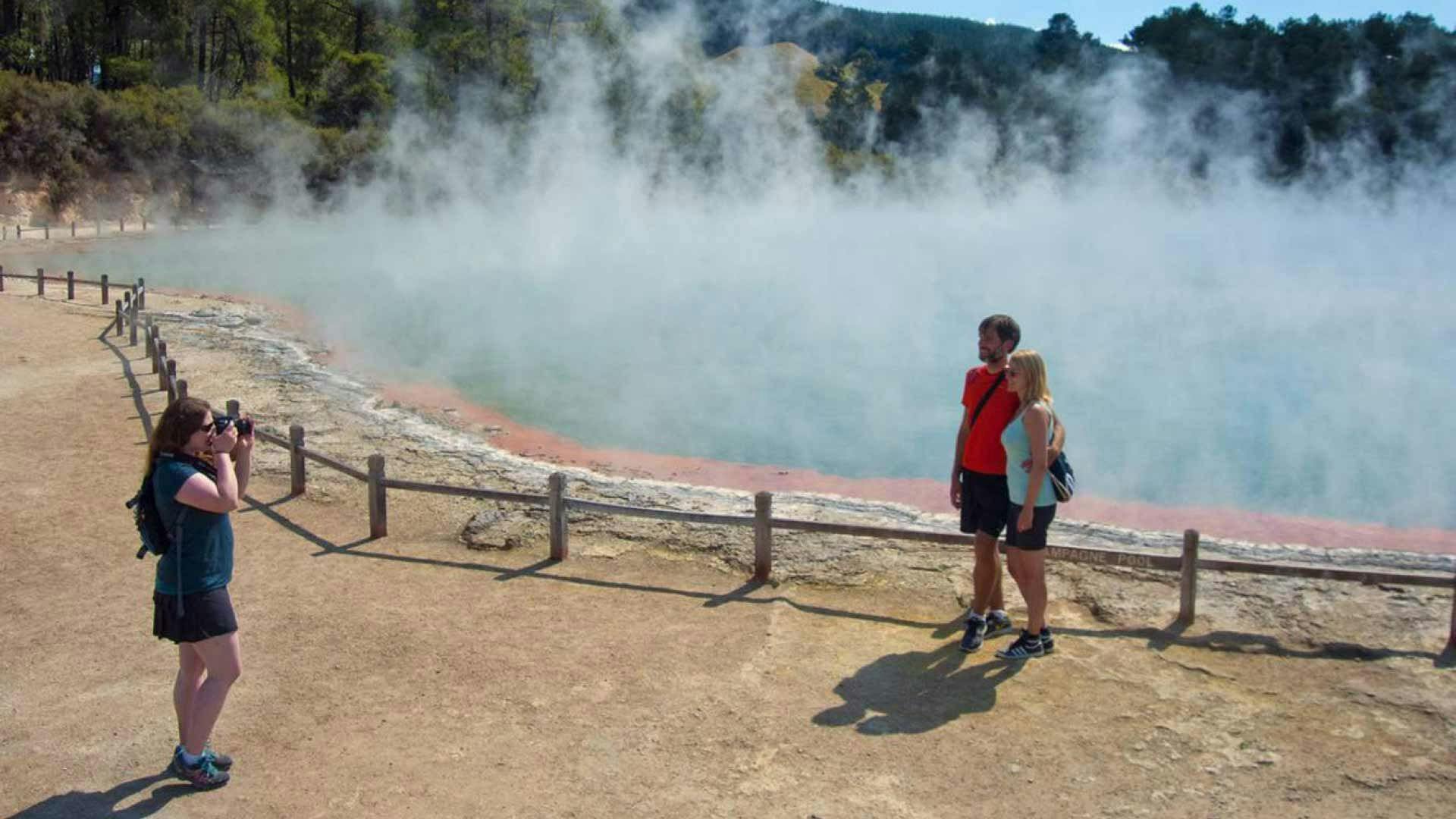 Couple get a photo in front of some geothermal activity in Rotorua