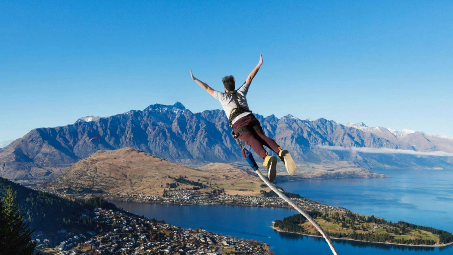 Man bungy jumping with a view over Queenstown