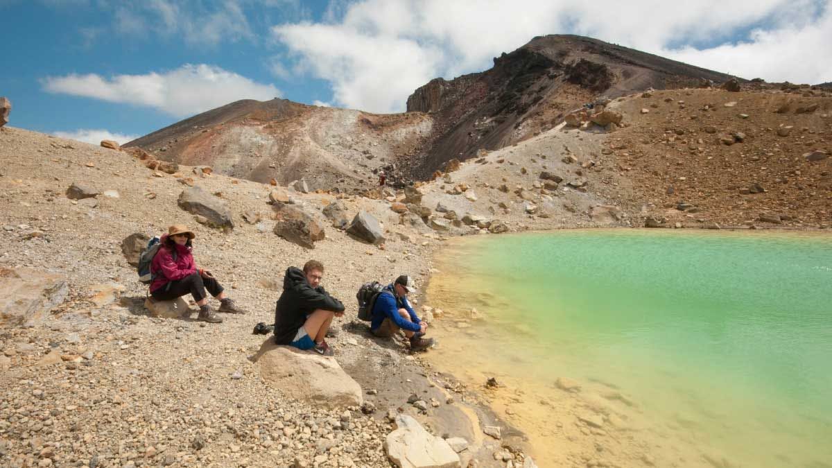 Group of hikers sitting next to an Emerald lake on the Tongariro Crossing