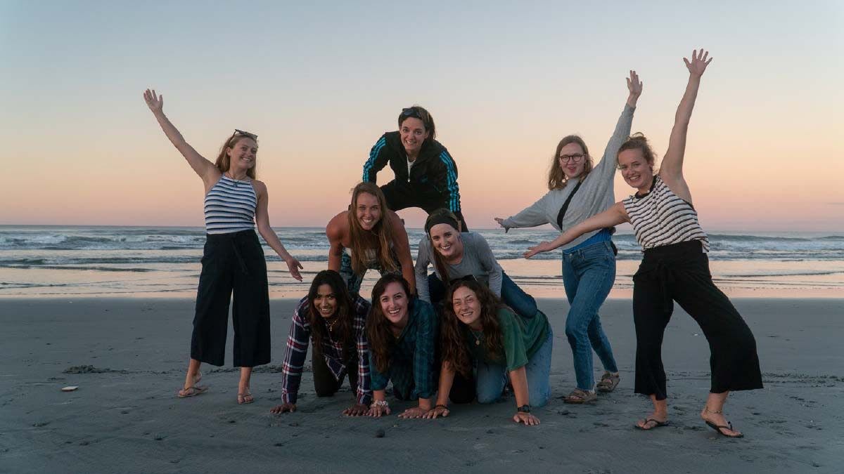Group of friends pose for a photo on a west coast beach in New Zealand